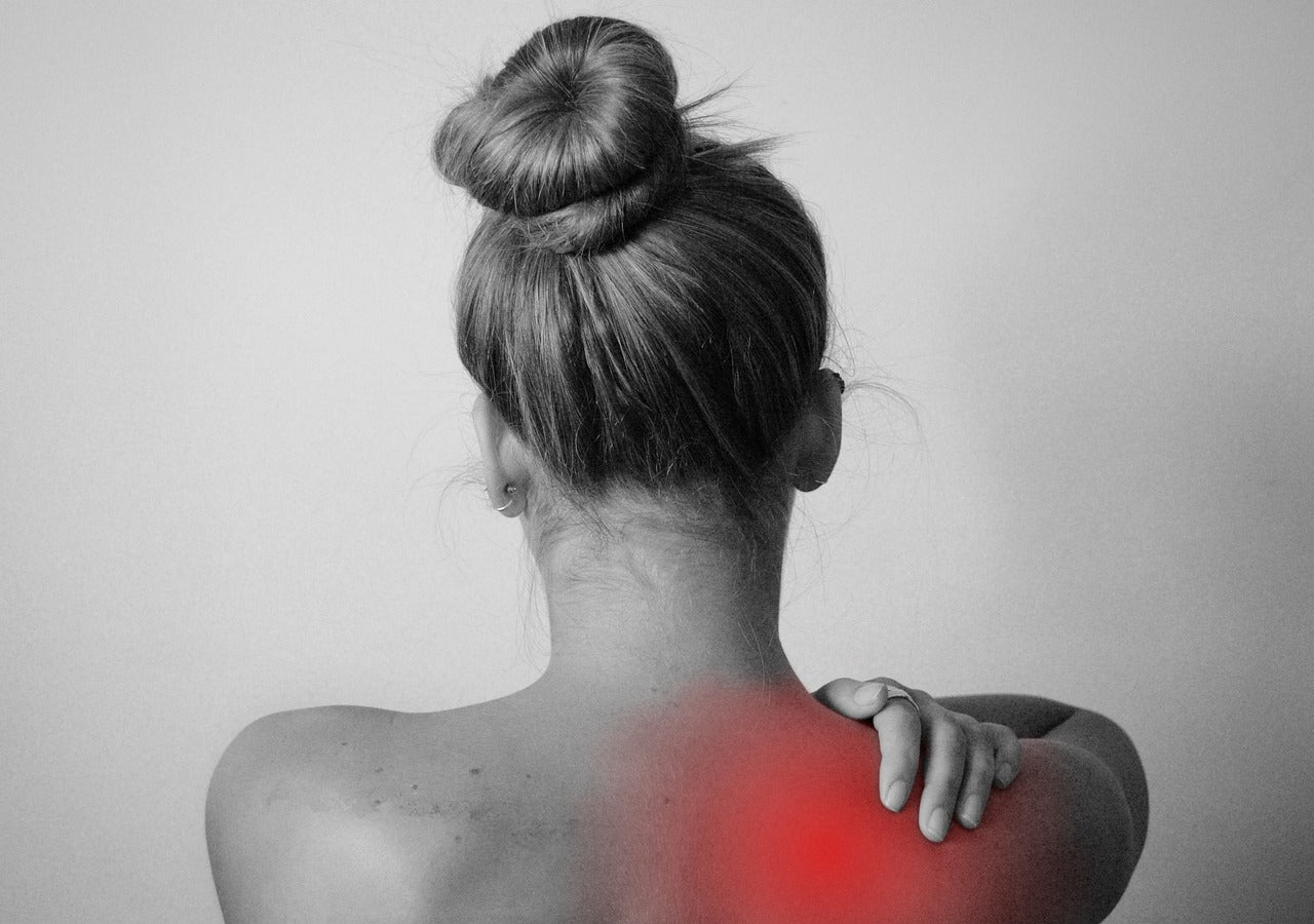 A woman holding her lower back in pain, representing the struggles of chronic illness and the mind-body connection